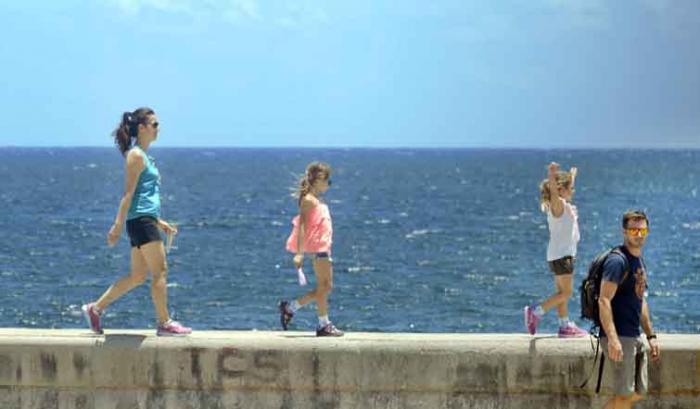 Personas caminando por el muro del Malecón habanero.