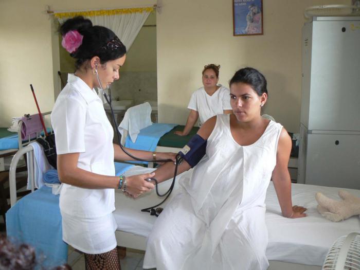 Enfermera tomando la presión a una mujer embarazada.