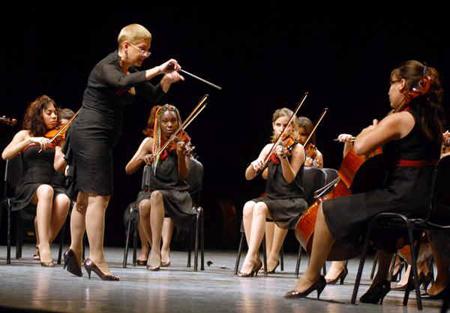 mujeres tocan instrumentos, mujer dirige orquesta, sala de conciertos