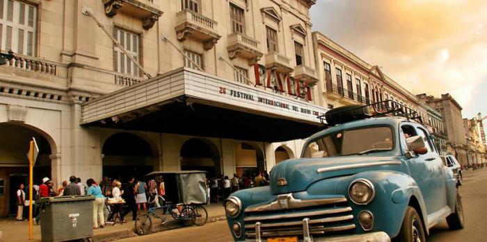 la imagen muestra un auto, fachada de un edificio y personas
