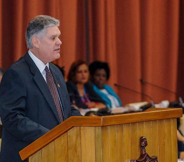 hombre habla, tribuna, micrófono, mujeres miran