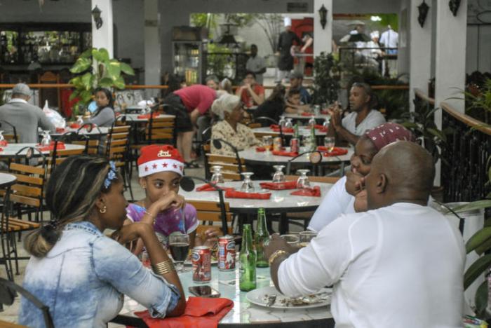La imagen muestra varias personas sentadas en mesas, interior