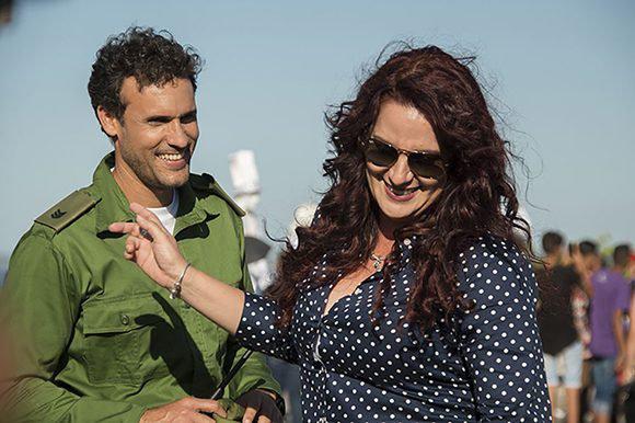 mujer y hombre sonríen, personas en fondo de la imagen