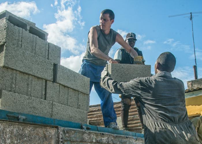 Estibadores descargan materiales de construcción para viviendas de damnificados por el tornado en La Habana