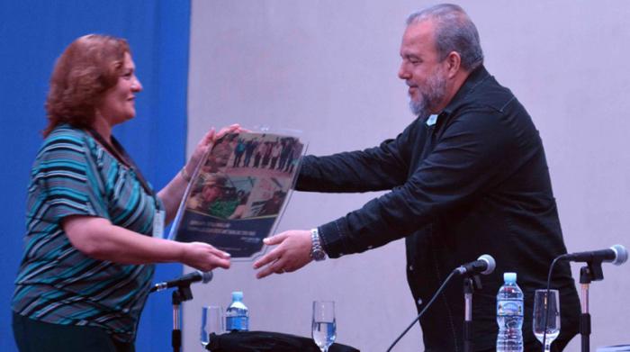 El Primer Ministro Manuel Marrero Cruz (D), recibe una placa conmemorativa por los 32 años de fundada la Agricultura Urbana, Suburbana y Familiar, dedicada al General de Ejército Raúl Castro Ruz, durante el Balance Nacional realizado en el cine de Mayarí Arriba, municipio de II Frente, en Santiago de Cuba, el 15 de febrero de 2020. ACN  FOTO/ Miguel RUBIERA JÚSTIZ/ rrcc