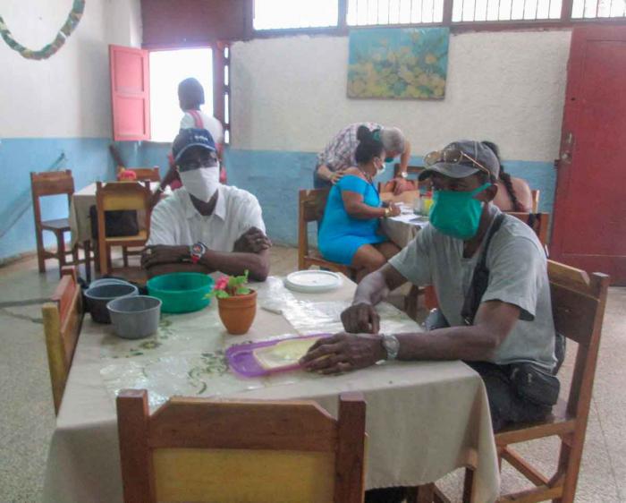 personas esperando en un comedor por alimentos en el sistema de atencion a la familia