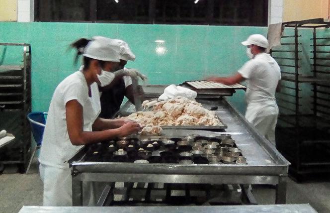 personas haciendo pan y dulces en una panaderia 