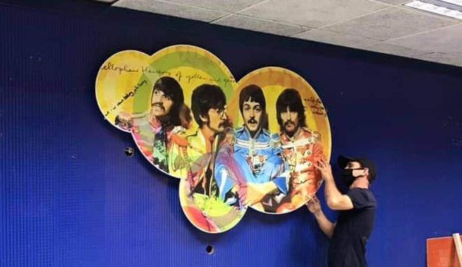 Persona colocando un cartel con la imagen de los Beatles, en el Submarino Amarillo