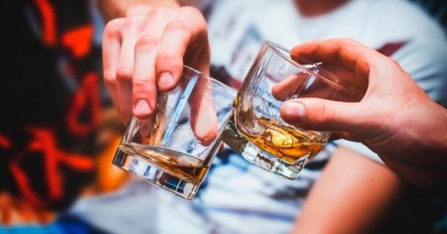 Dos vasos con bebidas alcohólicas, dos manos brindando