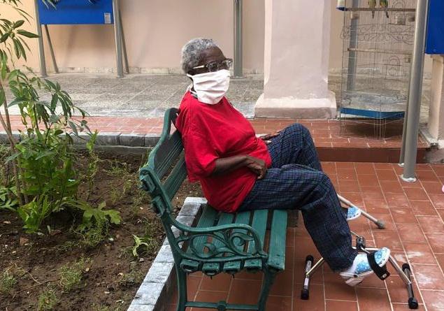 Una señora sentada en un banco, en uno de los aparatos para hacer ejercicios con los pies