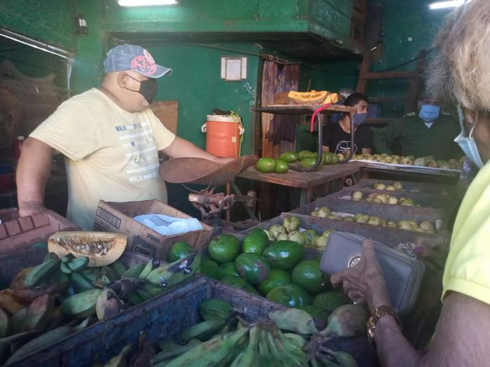 Un vendedor despacha productos en un agromercado a una cliente