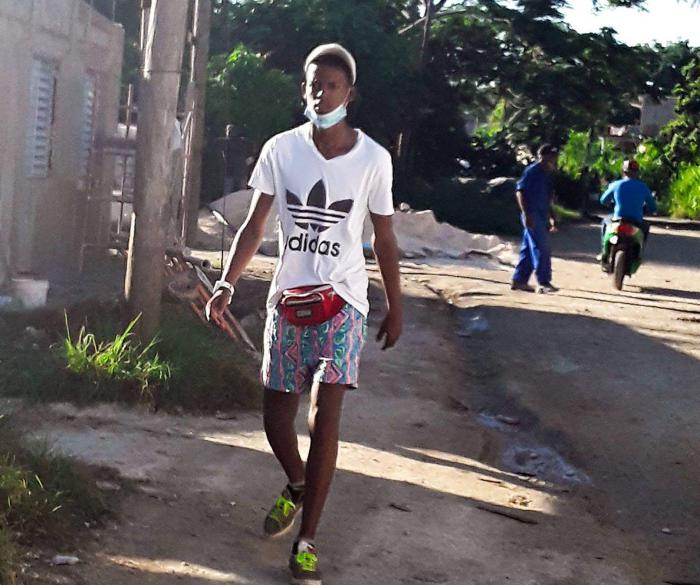 Persona caminando por la acera con el nasobuco mal puesto