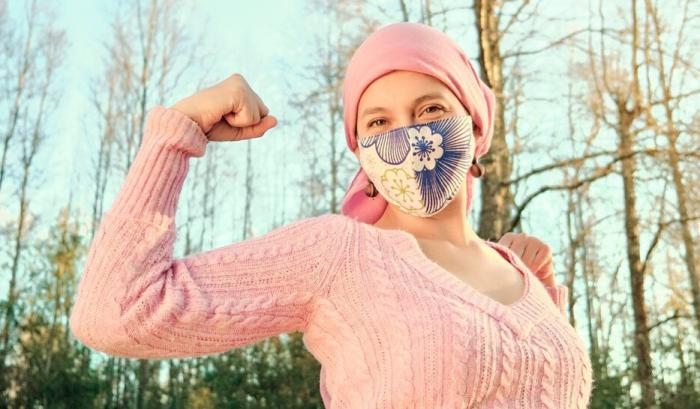 Una mujer con cáncer haciendo un ademán de fortaleza ante la enfermedad