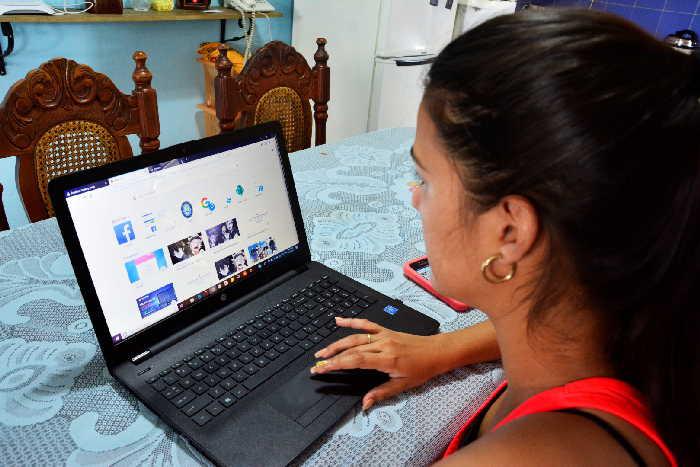 Una mujer sentada a la mesa con una laptop, realizando teletrabajo