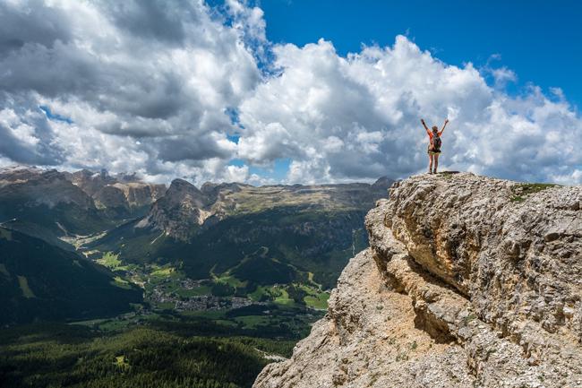 persona en una montaña, al fondo varias montañas y el cielo