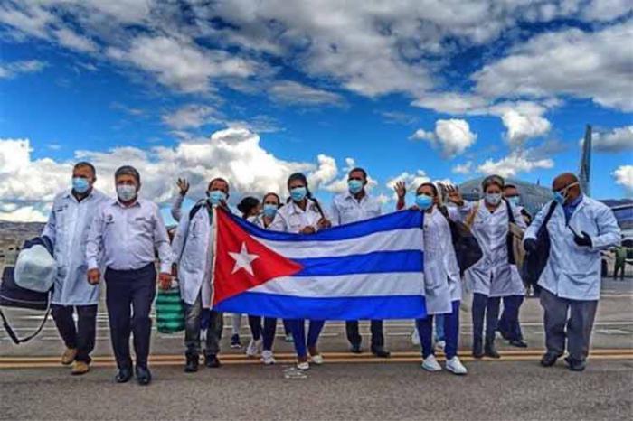 Médicos cubanos que llegan de una misión, llevan una bandera cubana 