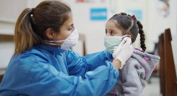 Una mujer poniendo el nasobuco a una niña