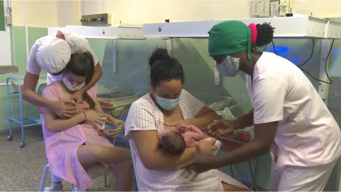Dos mamás amamantando a sus bebés, con ayuda del personal de salud