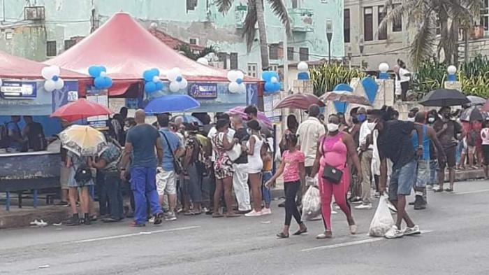 Personas por el malecón, algunas compran en unas carpas