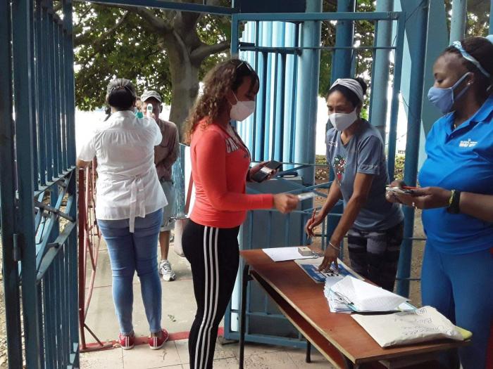 Una mujer recoge su dorsal en el local de entrega donde atienden dos personas