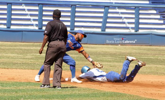 Un jugador de Industriales regado en el campo para alcanzar la base, le cogen out