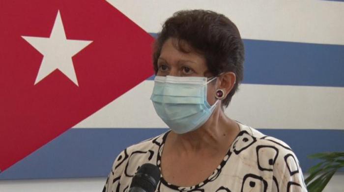 Ena Elsa Velázquez, al fondo la bandera cubana