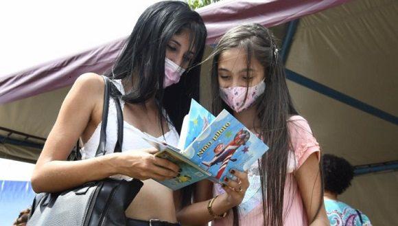 Una muchacha y una niña miran un libro