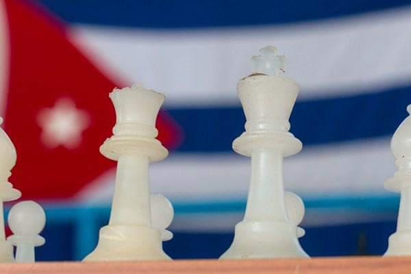 Piezas de ajedrez, al fondo la bandera cubana.