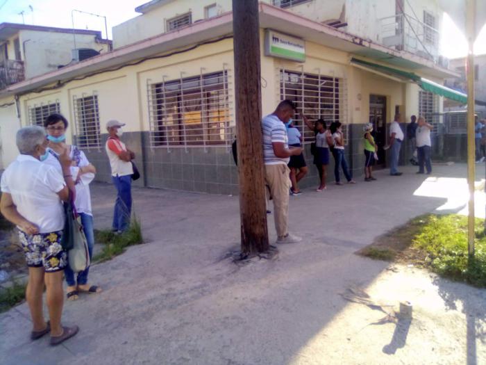 Personas esperando afuera del banco del reparto Casino Deportivo del Cerro.