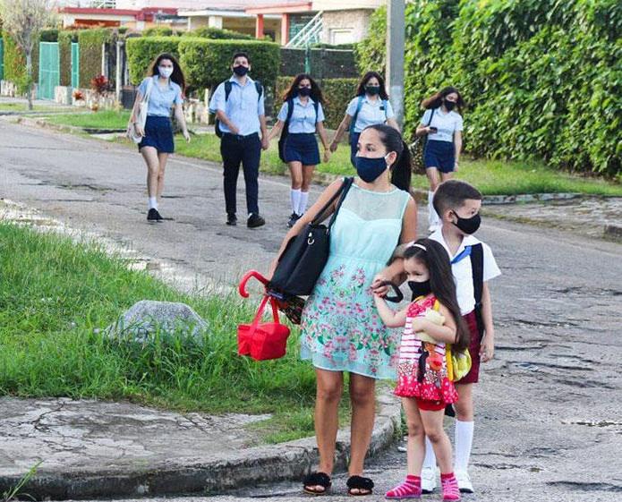 Niño estudiante de pirmaria y niña de círculo infantil con su mamá y estudiantes de preuniversitario