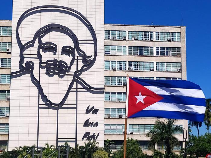 Imagen de Camilo en edificio de la Plaza de la Revolución y bandera cubana