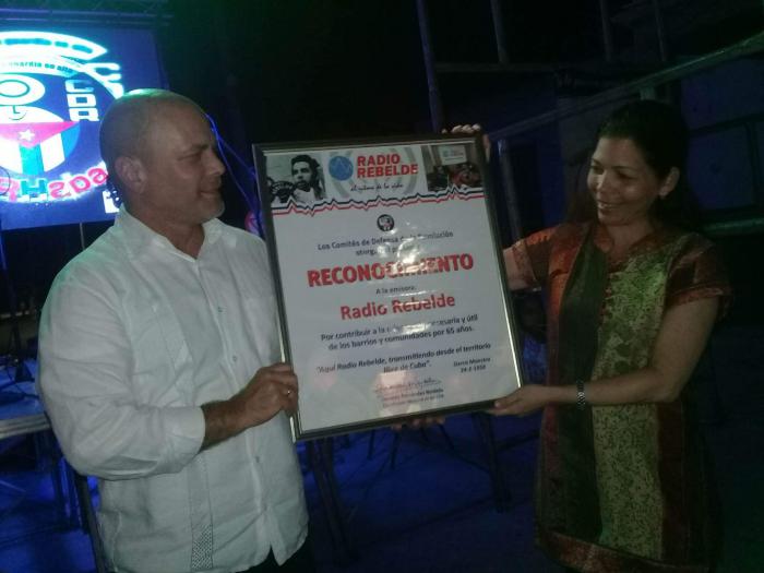Liuba Moreno, directora general de Radio Rebelde, recibió de manos del Coordinador Nacional de los CDR el reconocimiento por el aniversario 65 de la emisora