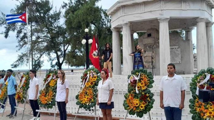 Estudiantes al lado de las ofrendas florales