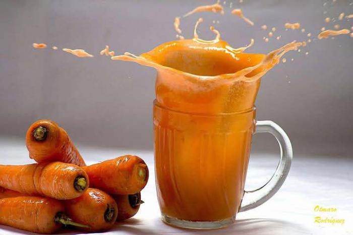 Jugo de zanahoria en una jarra y varias zanahorias crudas
