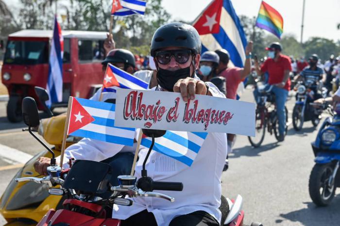 Persona con banderas cubanas y cartel de Abajo el bloqueo