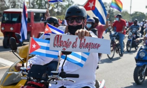 Persona con banderas cubanas y cartel de Abajo el bloqueo