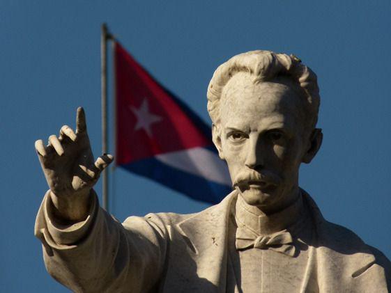 Escultura de José Martí y al fondo la bandera cubana