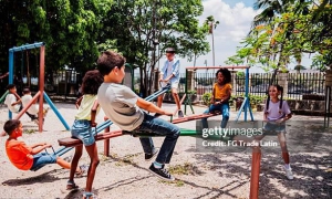 Child friends playing on seesaw at public park. Niños jugando en un parque.